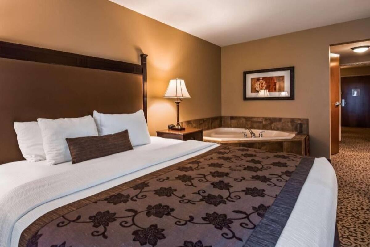 A hotel room with a large bed, a bathroom with a bathtub, and a framed picture on the wall.