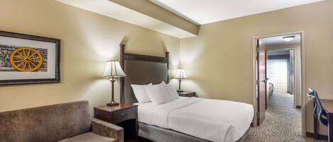 Una habitación de hotel con cama, sofá, escritorio y lámpara.