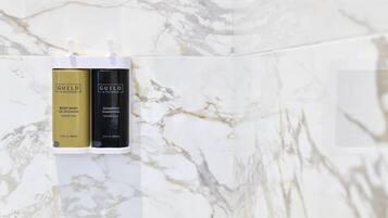 Two bottles of Guilt + Pepper body wash and shampoo on a marble surface.