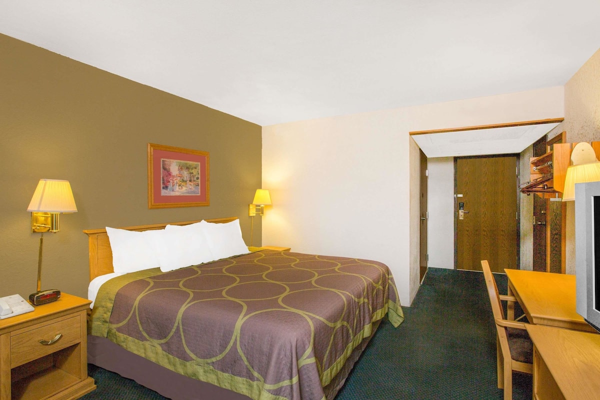 Ein Hotelzimmer mit einem Bett, Nachttischlampen, einem Schreibtisch und einem Stuhl.