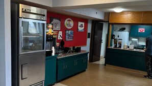 A kitchen with a stainless steel refrigerator, a coffee machine, and a teal-colored counter.