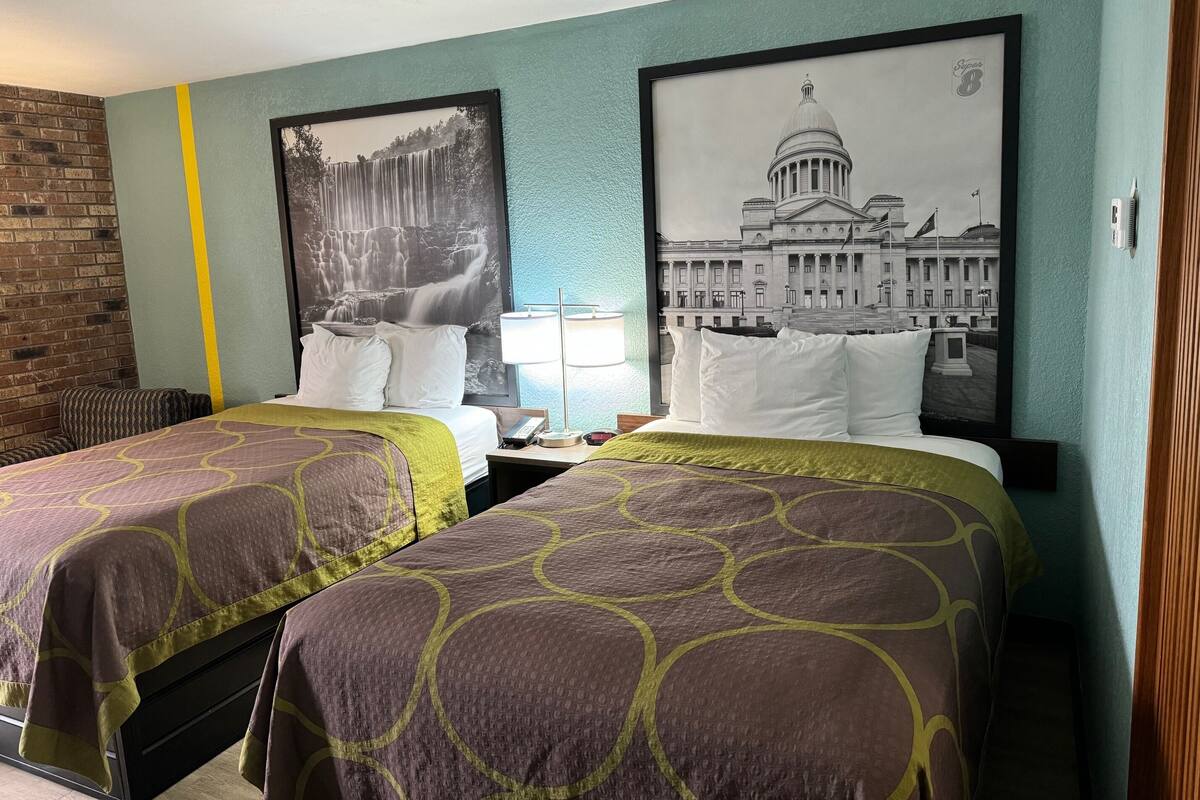 Ein Hotelzimmer mit zwei Betten, einer Ziegelwand und zwei großen schwarz-weiß Fotografien an der Wand.