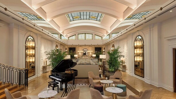 A grand lobby with a grand piano, seating areas, a bar, and a staircase. - Sheraton Grand London Park Lane (London)