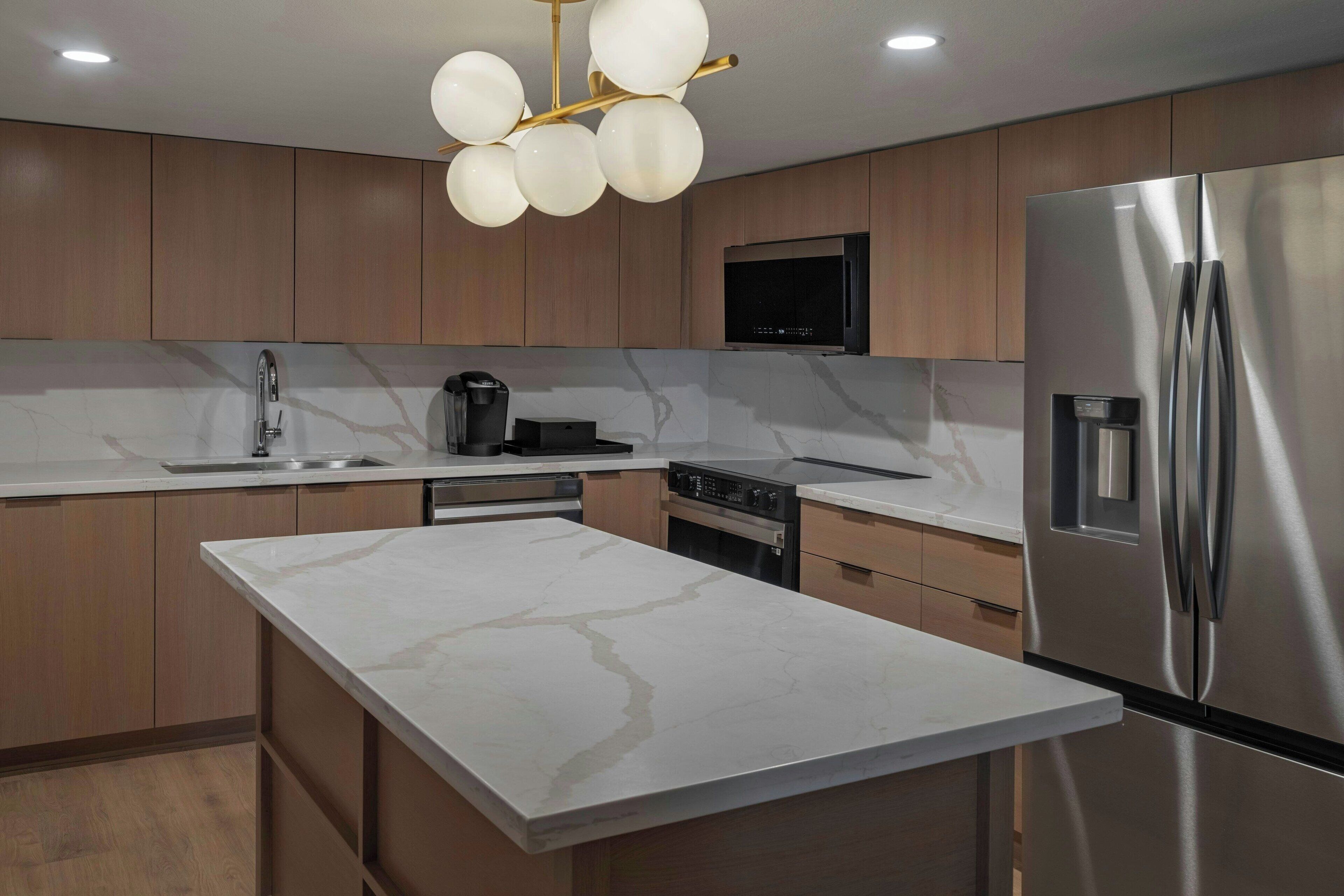 Una cocina moderna con una isla grande, electrodomésticos de acero inoxidable y armarios de madera.