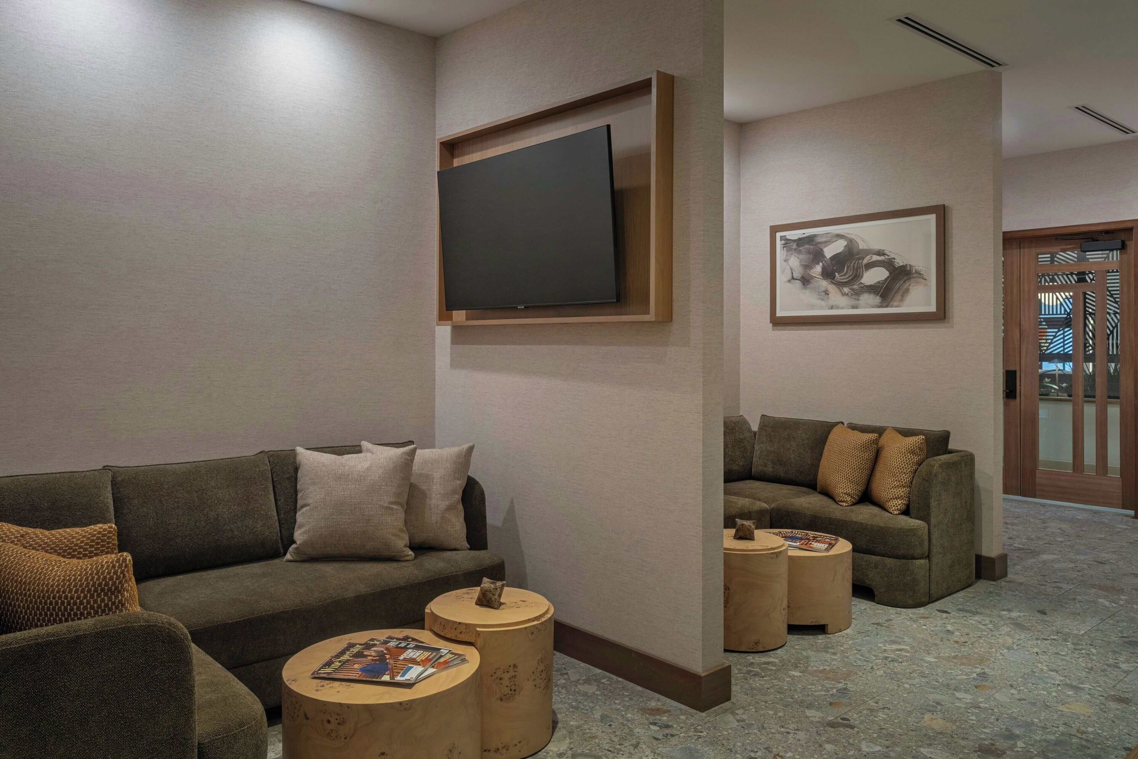 A modern living room with sofas, a flat-screen TV, and a framed artwork on the wall.