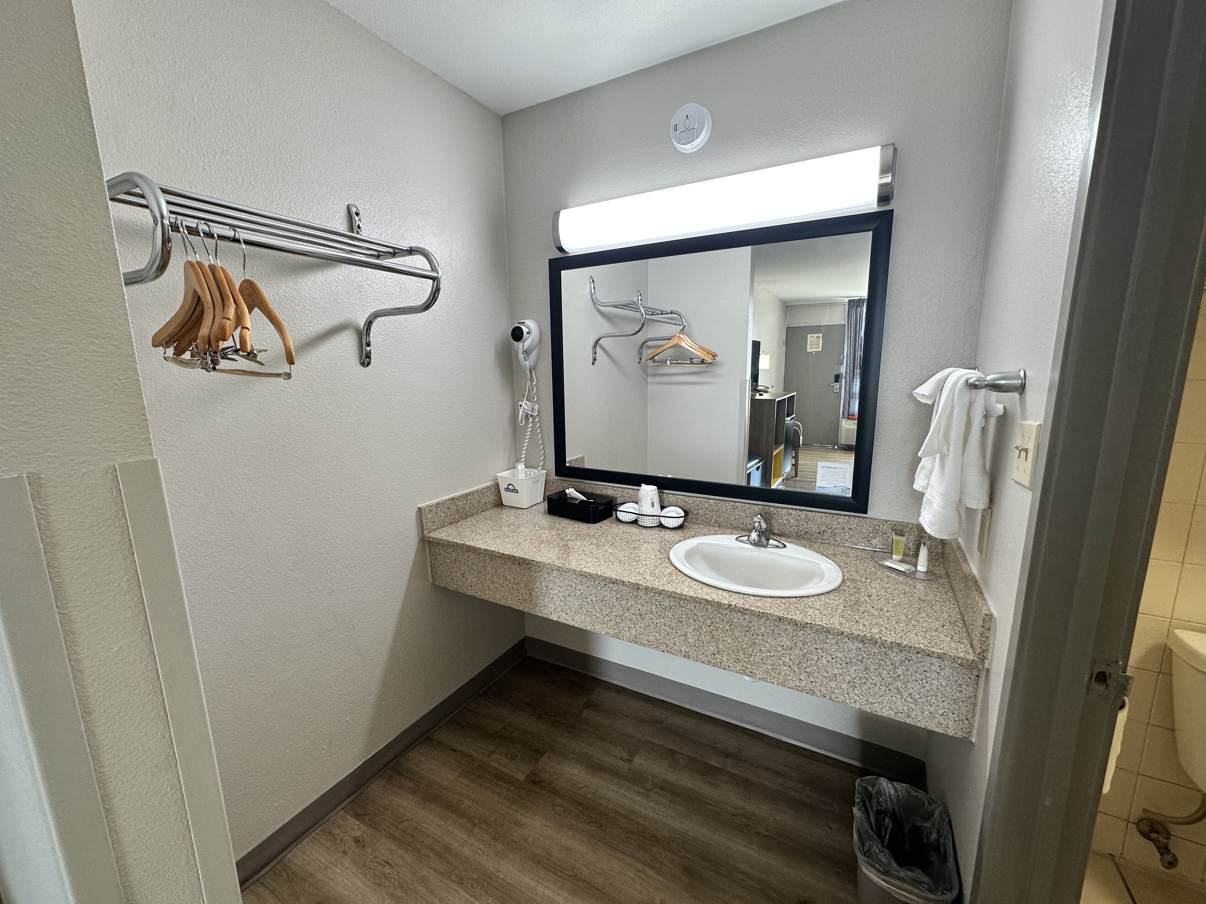 Un baño con lavamanos, espejo, toallero y secador de pelo.