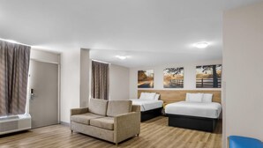 Une chambre d’hôtel avec un canapé, deux lits et une fenêtre avec des rideaux.
