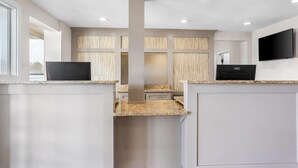 Une cuisine moderne dotée de plans de travail en granit, de meubles blancs et d’un îlot central.