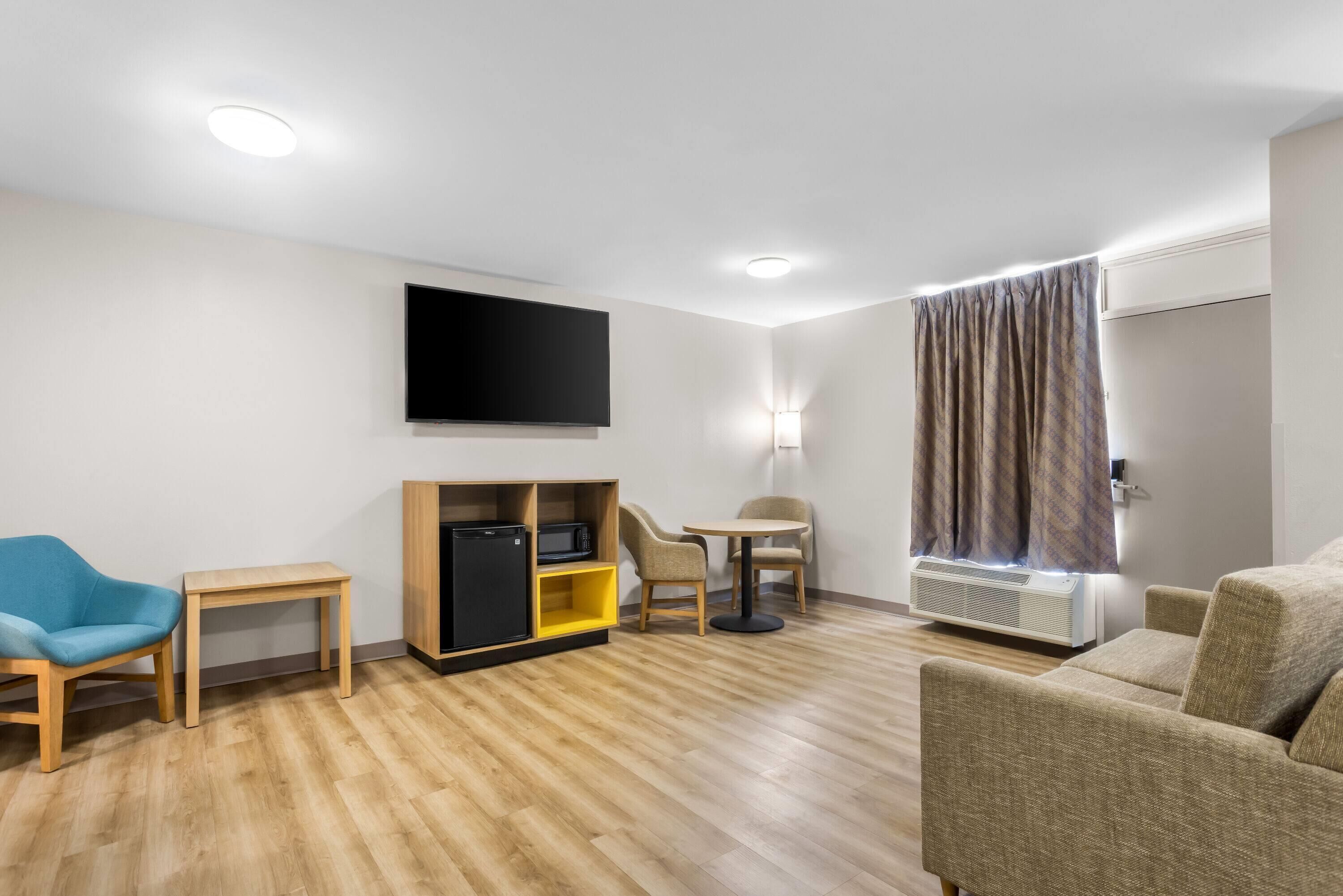A modern living room with a flat-screen TV, a small table, a sofa, and a chair.