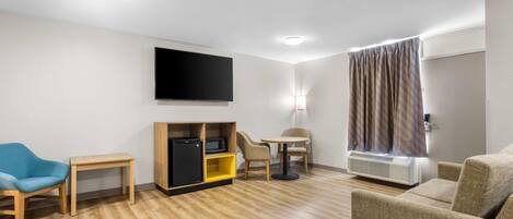 A modern living room with a flat-screen TV, a small table, a sofa, and a chair.
