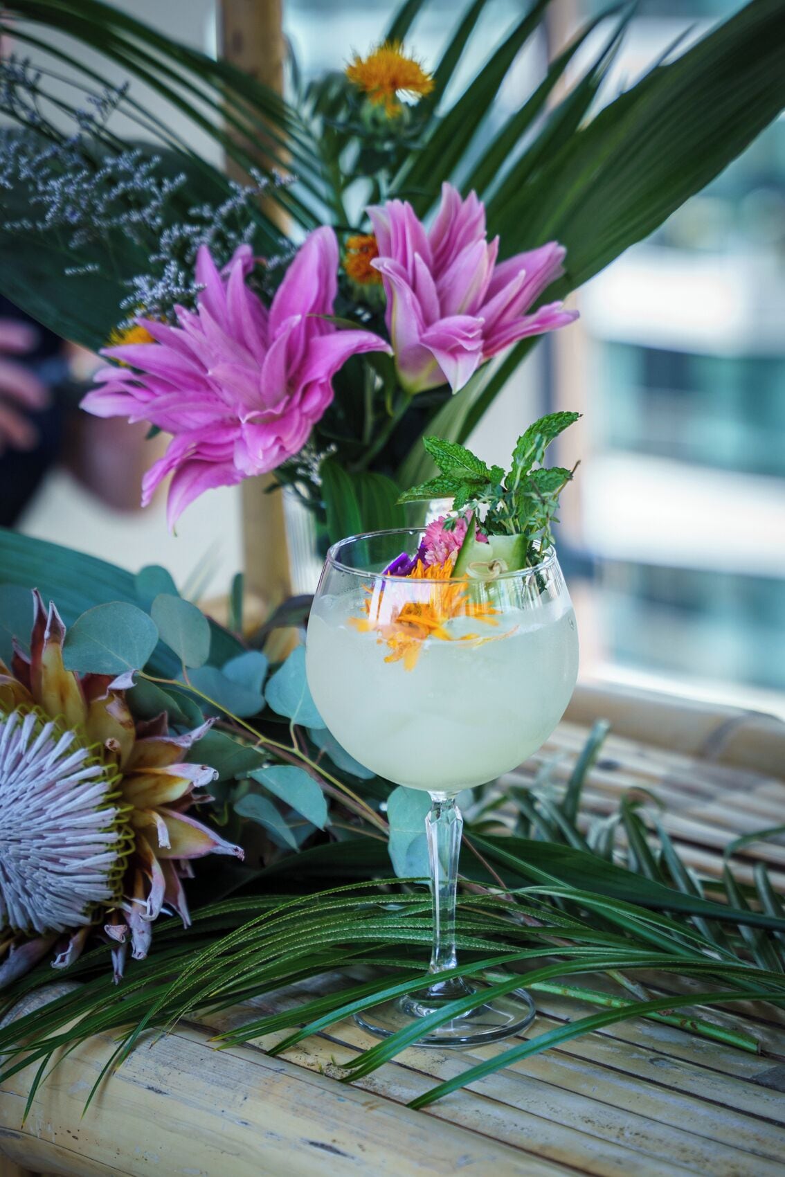 A cocktail glass with a floral garnish on a wooden surface.