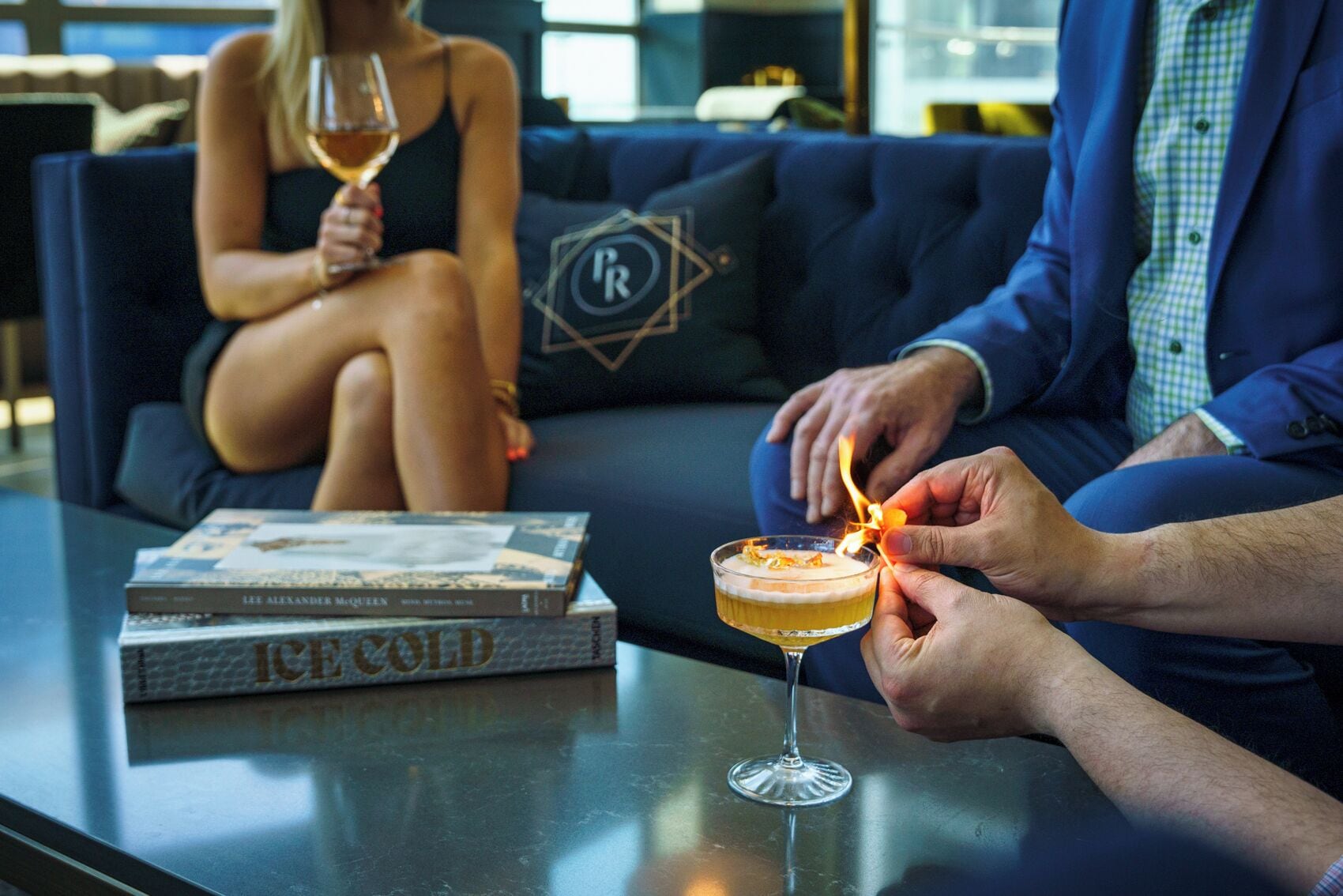 Une personne allume une bougie sur une table, à côté d’un livre intitulé « Froid glacial » et d’un verre de vin.