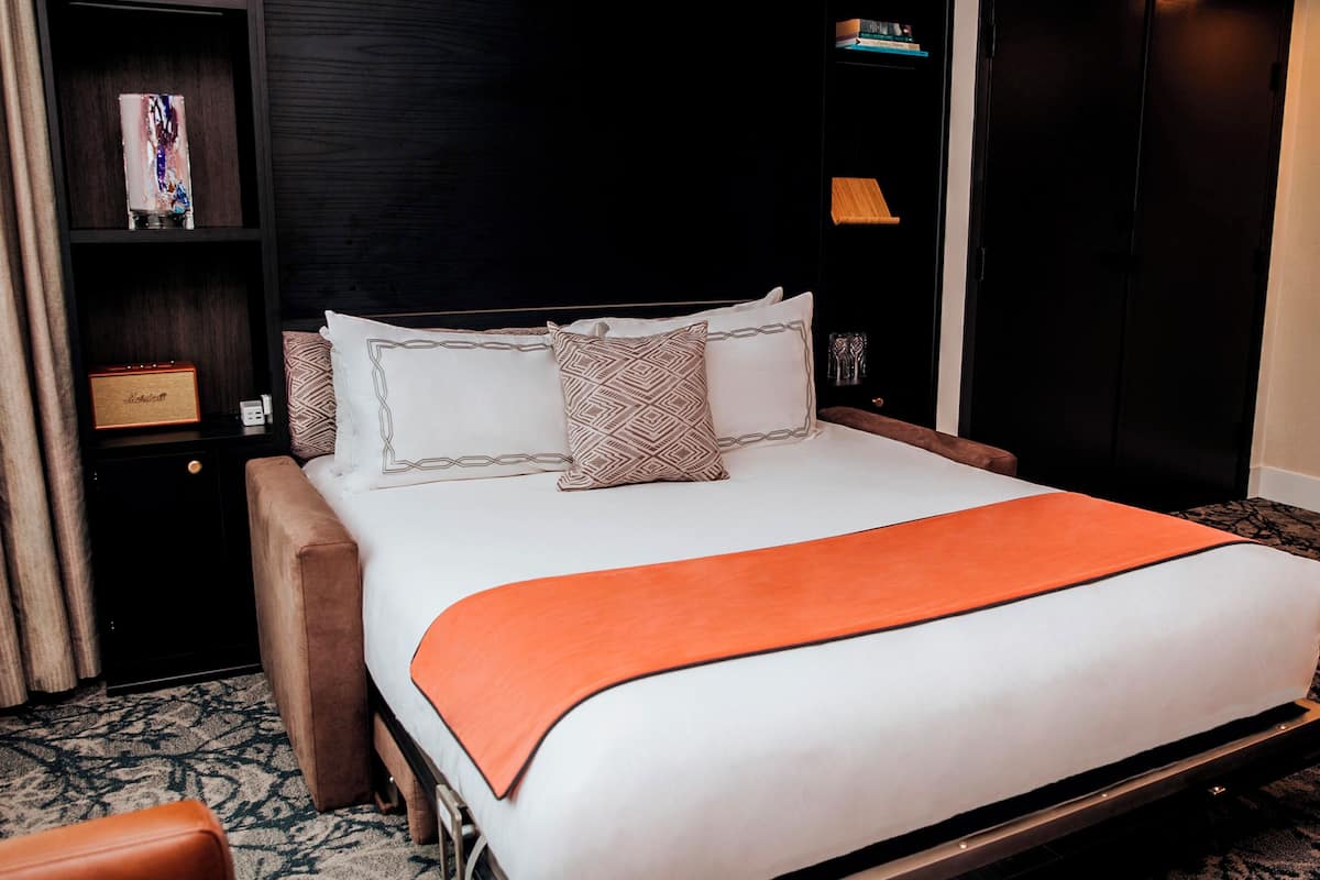 A hotel room with a bed, a nightstand, a bookshelf, and a wardrobe.