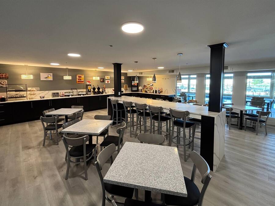 En modern restaurang med en bardel, flera olika typer av sittplatser och utsikt över omgivningarna.