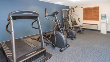 Un gimnasio con cintas de correr, elípticas y equipo de pesas.