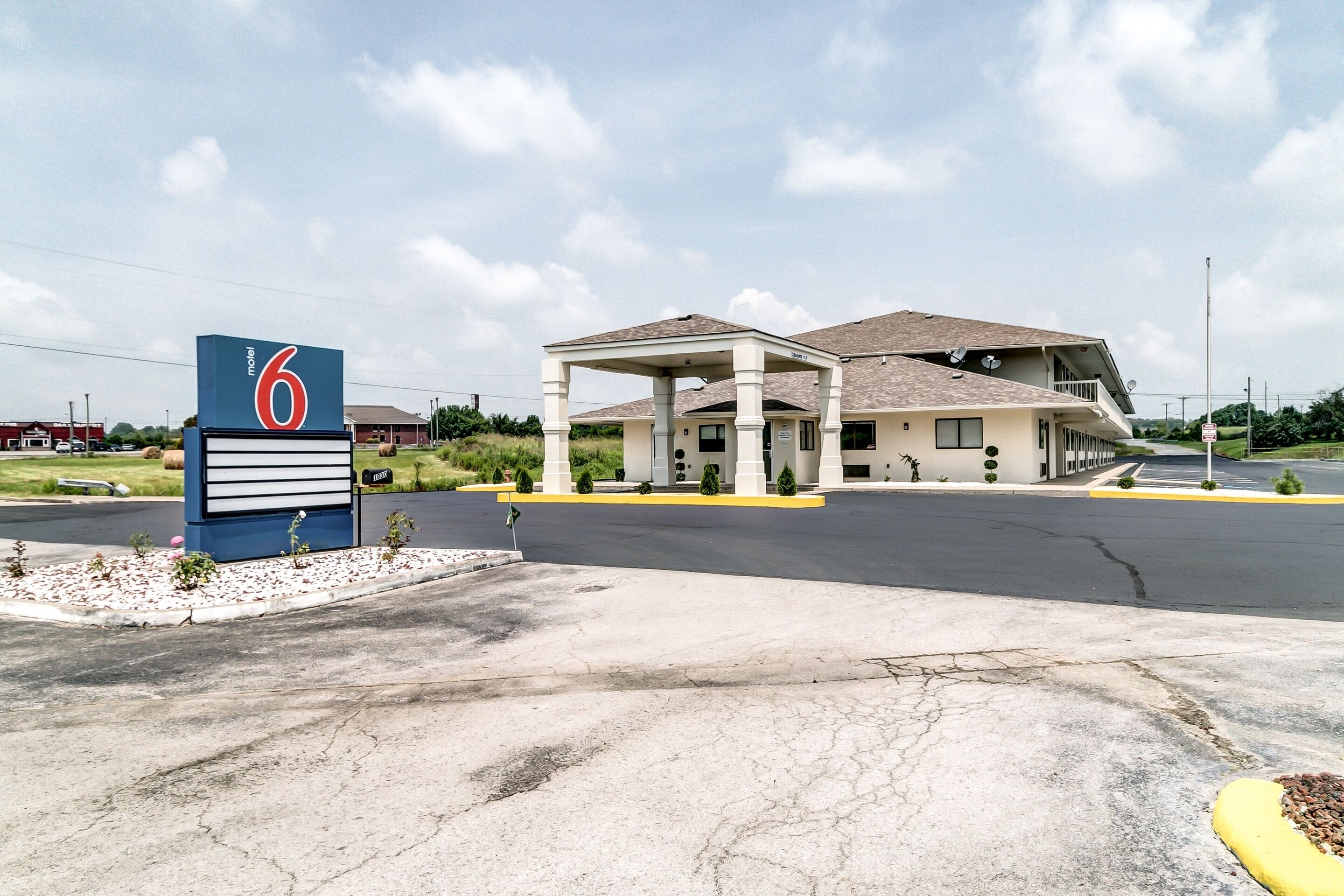 A motel with a large sign, a covered parking area, and a building with a sloped roof.