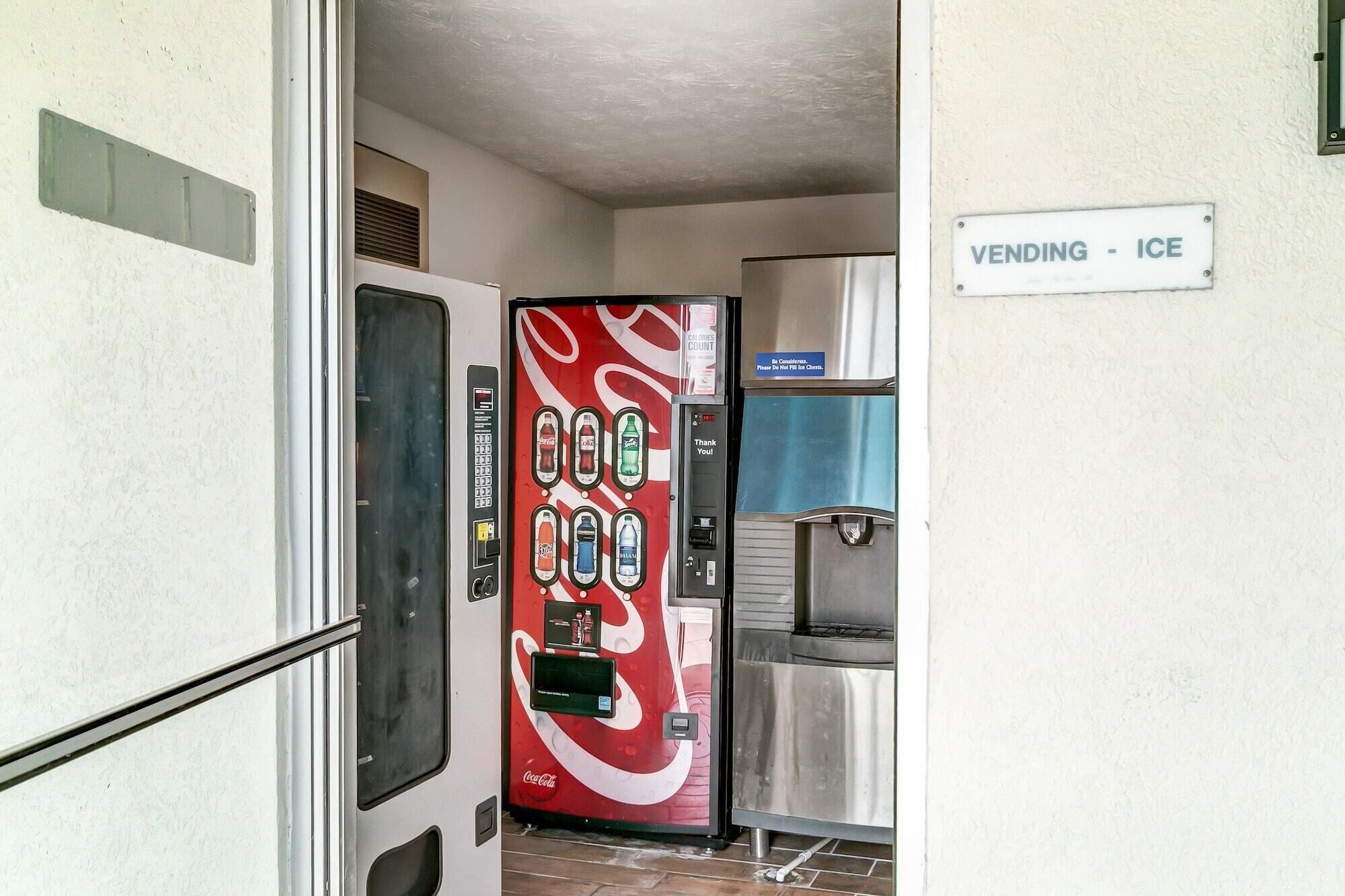 A vending machine with a Coca-Cola logo, a water dispenser, and a sign indicating a vending area.