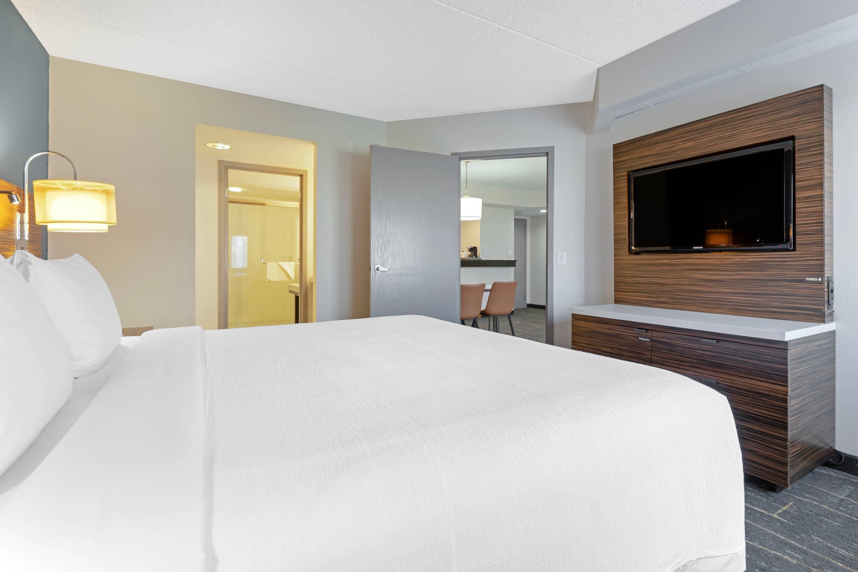 Une chambre d’hôtel avec un grand lit, un téléviseur fixé au mur et un bureau avec une chaise.
