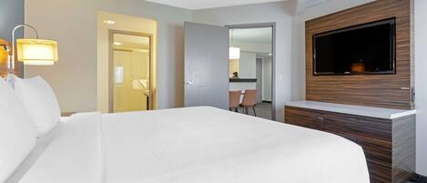 Habitación de hotel con una cama grande, un televisor montado en la pared y un escritorio con una silla.