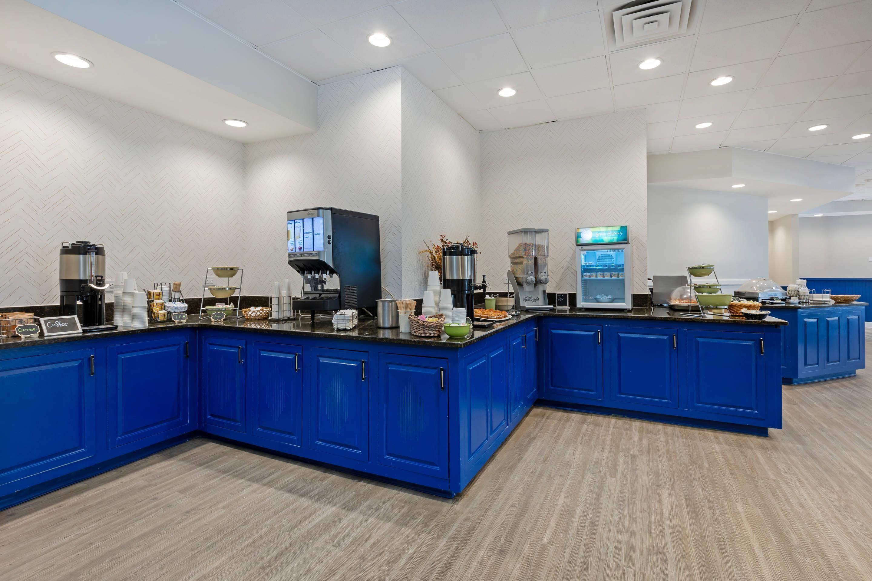 A modern kitchen with blue cabinets, a coffee station, and various appliances.