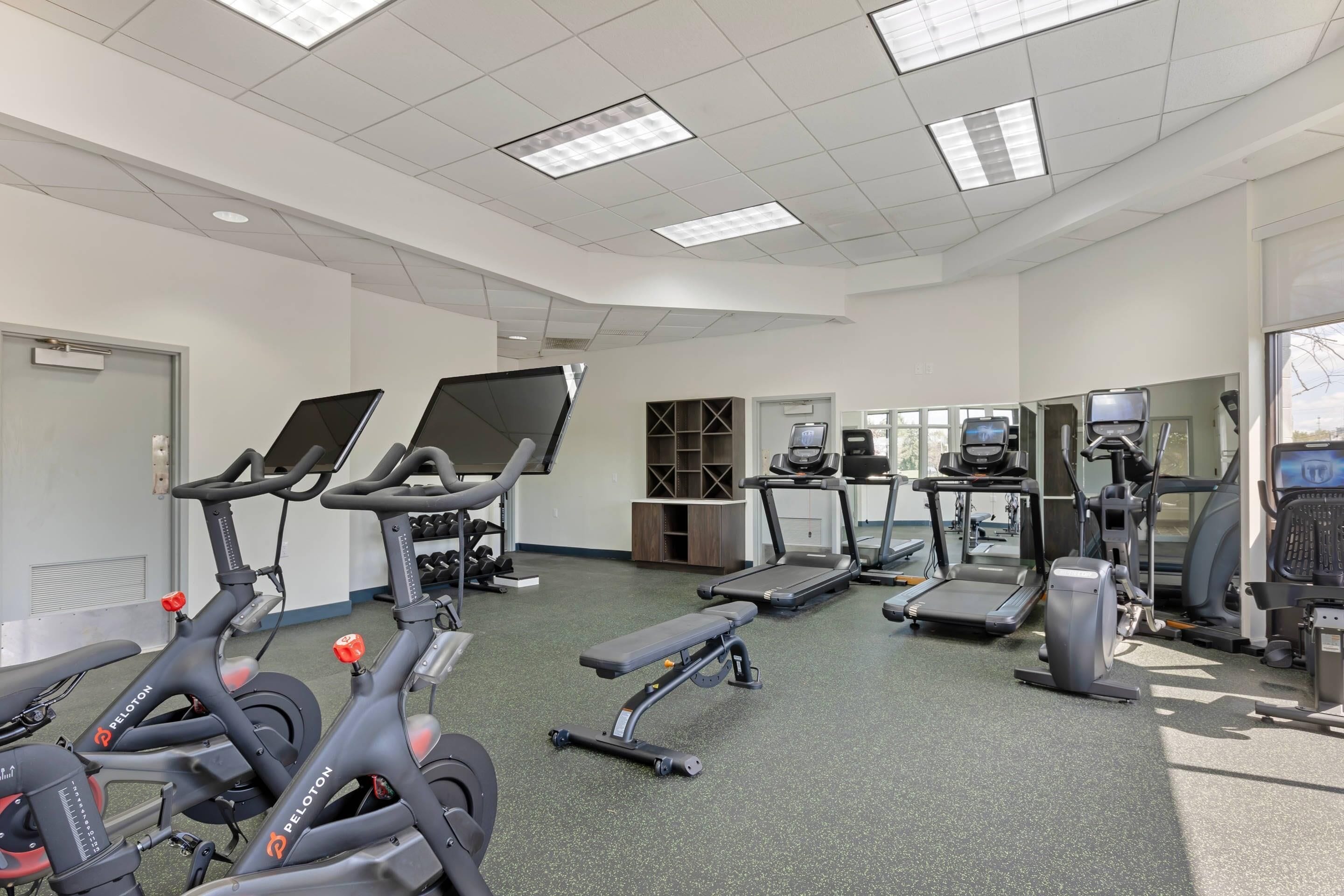 Un gimnasio con bicicletas estáticas, cintas de correr y elípticas.