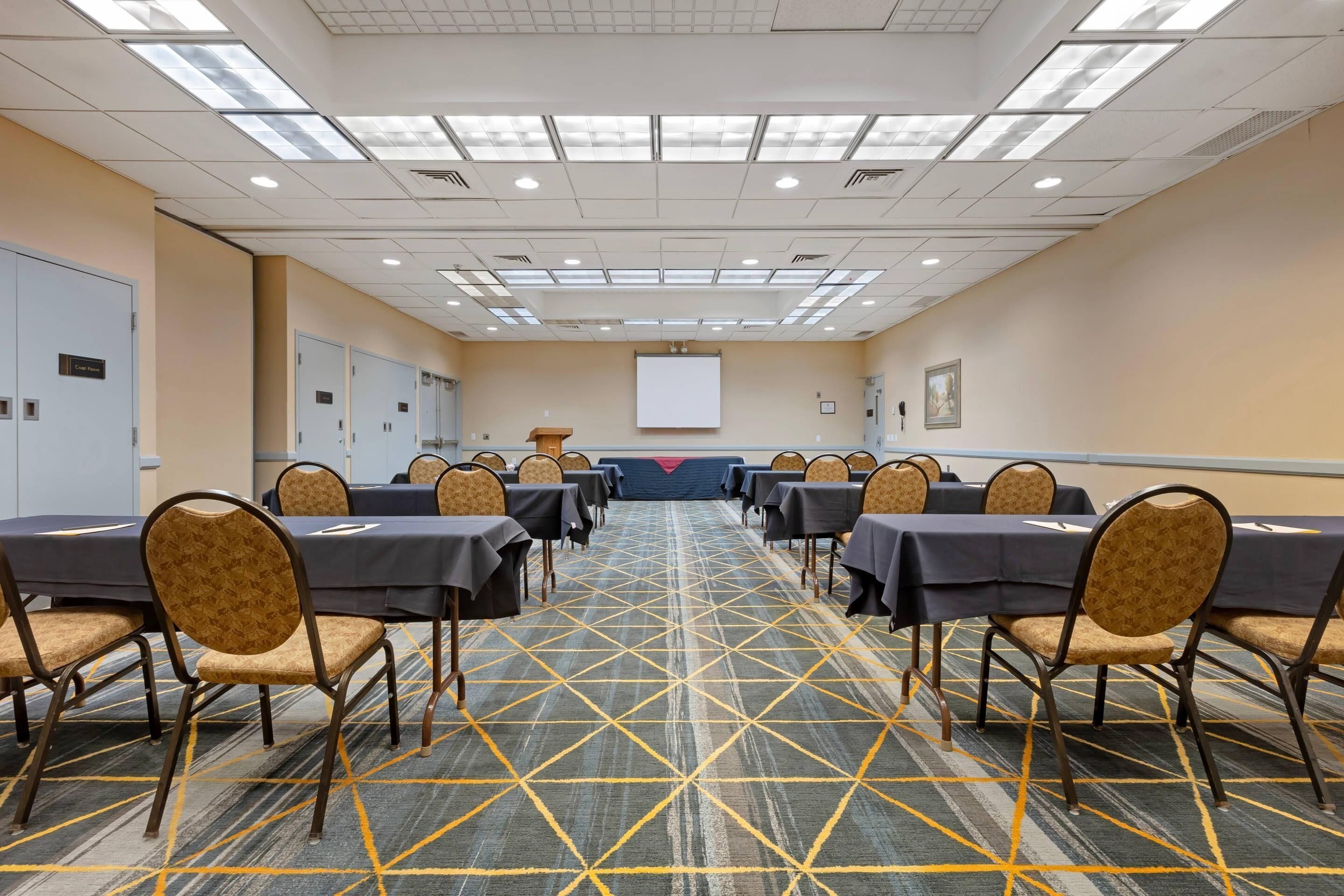 Un salón de conferencias con mesas y sillas dispuestas para una reunión.