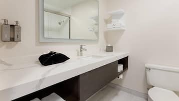 Un baño moderno con lavamanos de mármol, un espejo grande, un inodoro y toallas ordenadas.