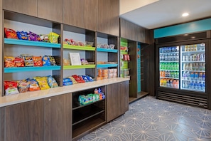 Un kiosque proposant des collations et des boissons, avec de nombreuses étagères remplies de produits et un présentoir réfrigéré pour les boissons.