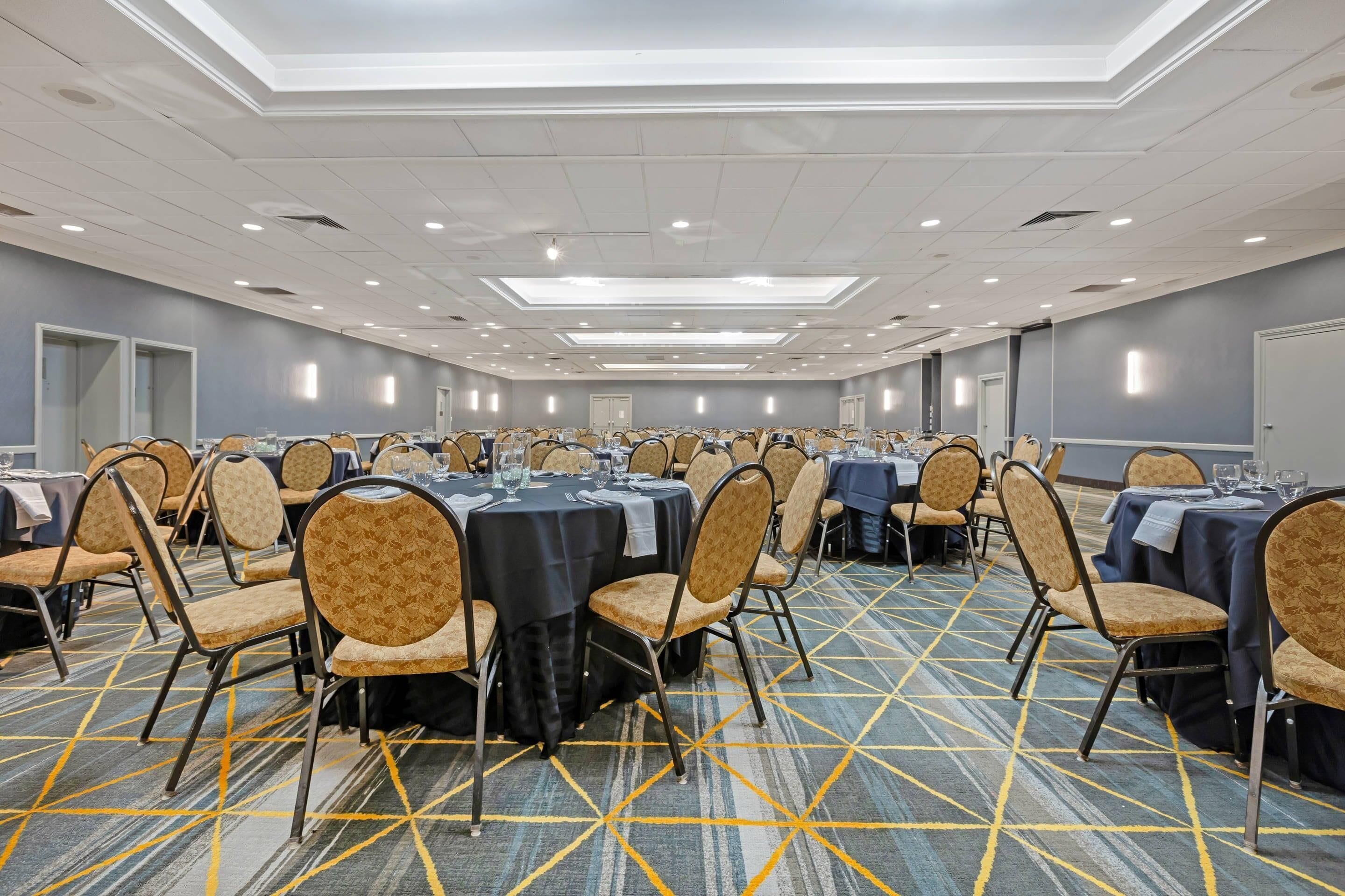 A conference room with multiple tables and chairs, arranged in rows.
