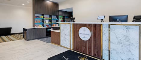 A reception area with a marble floor, a reception desk with a sign reading "The Lux Hotel Conference Center," and a welcome sign above the desk.