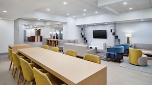 A modern conference room with a long table, yellow chairs, and a sofa area with blue and grey seating. - DoubleTree by Hilton Hotel Rocky Mount (Rocky Mount)