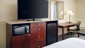 A hotel room with a flat-screen TV, a microwave, a mini-fridge, a desk with a chair, and a lamp. - DoubleTree by Hilton Hotel Rocky Mount (Rocky Mount)