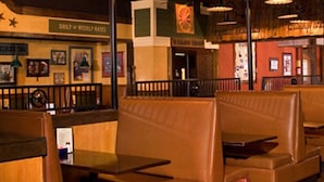 A restaurant interior with booths and tables, wooden furniture, and a menu stand. - DoubleTree by Hilton Hotel Rocky Mount (Rocky Mount)
