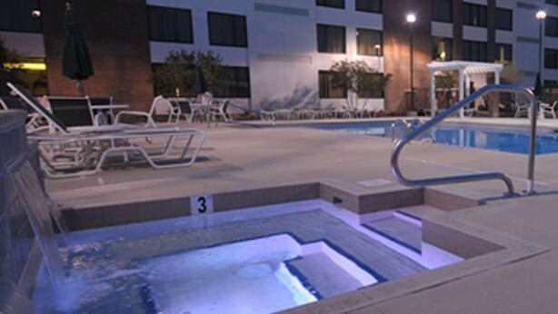 A hotel pool area with lounge chairs and a hot tub. - DoubleTree by Hilton Hotel Rocky Mount (Rocky Mount)