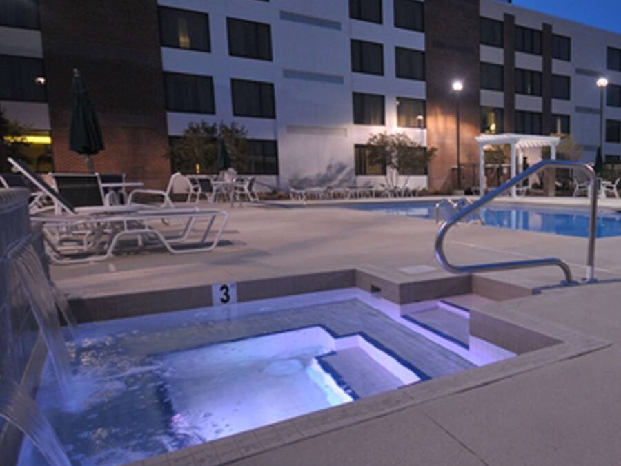 Una piscina al aire libre, sombrillas, sillones reclinables de piscina