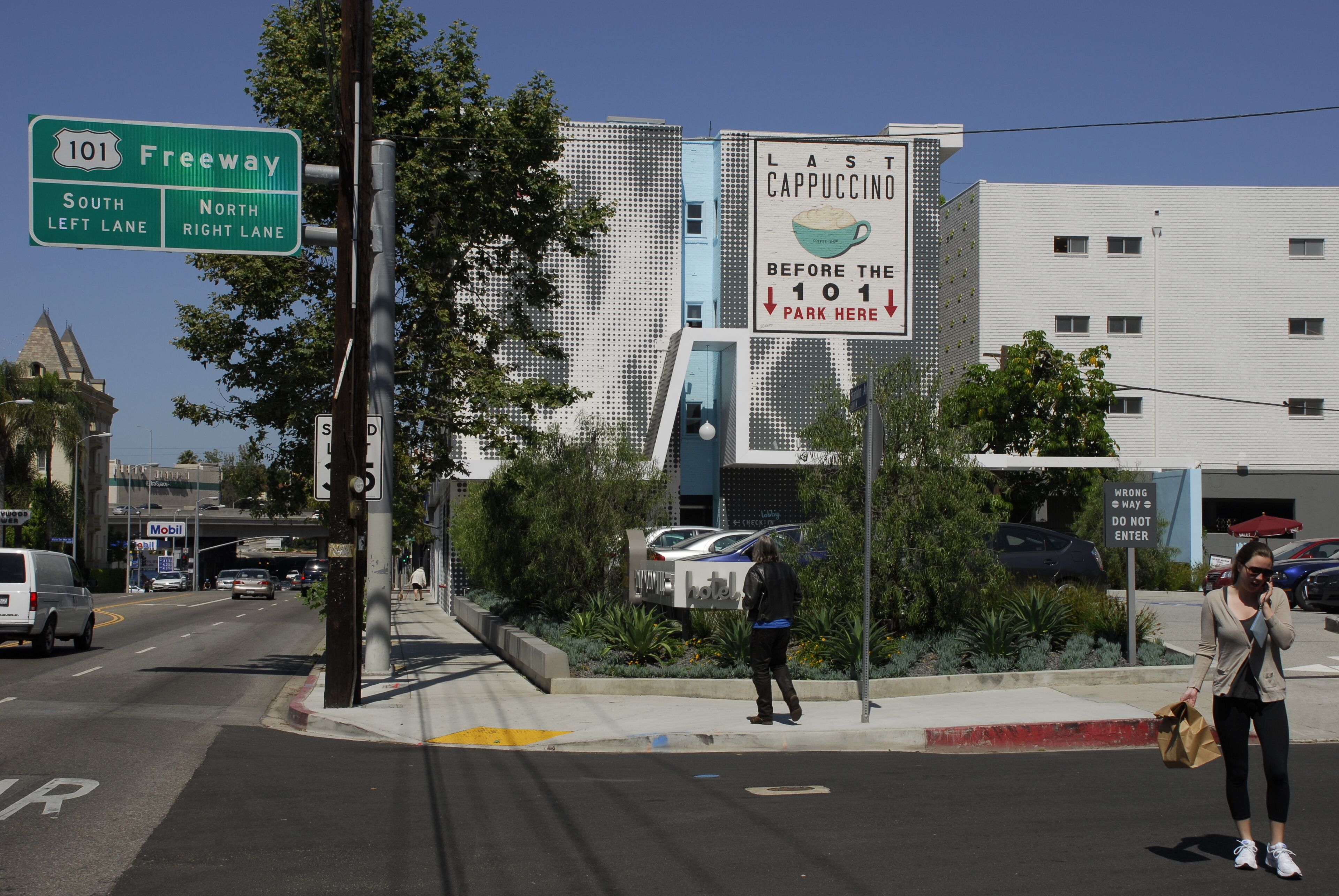 A street view with a sign for Freeway 101, a sign for the Last Cappuccino before the 101, and a hotel sign.