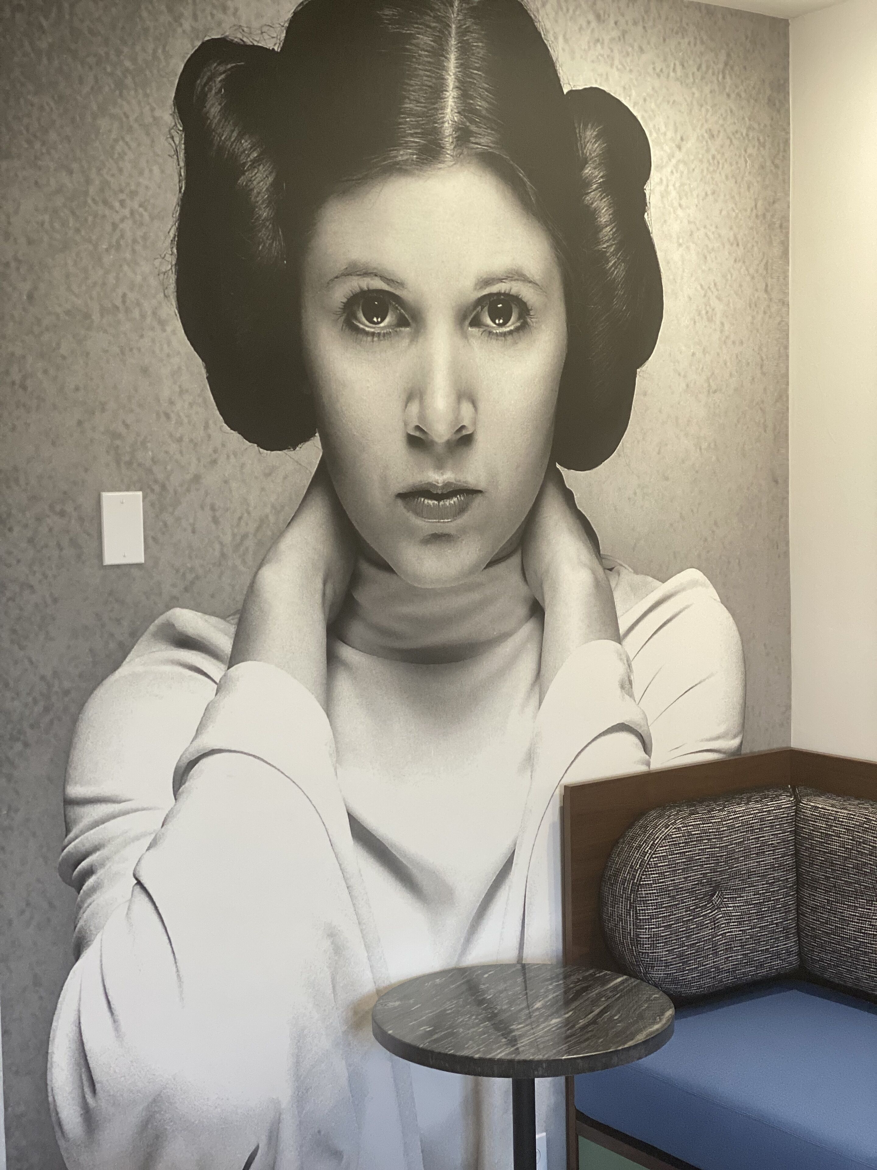 Una habitación con un papel tapiz decorativo, una pequeña mesa redonda y un sofá azul.
