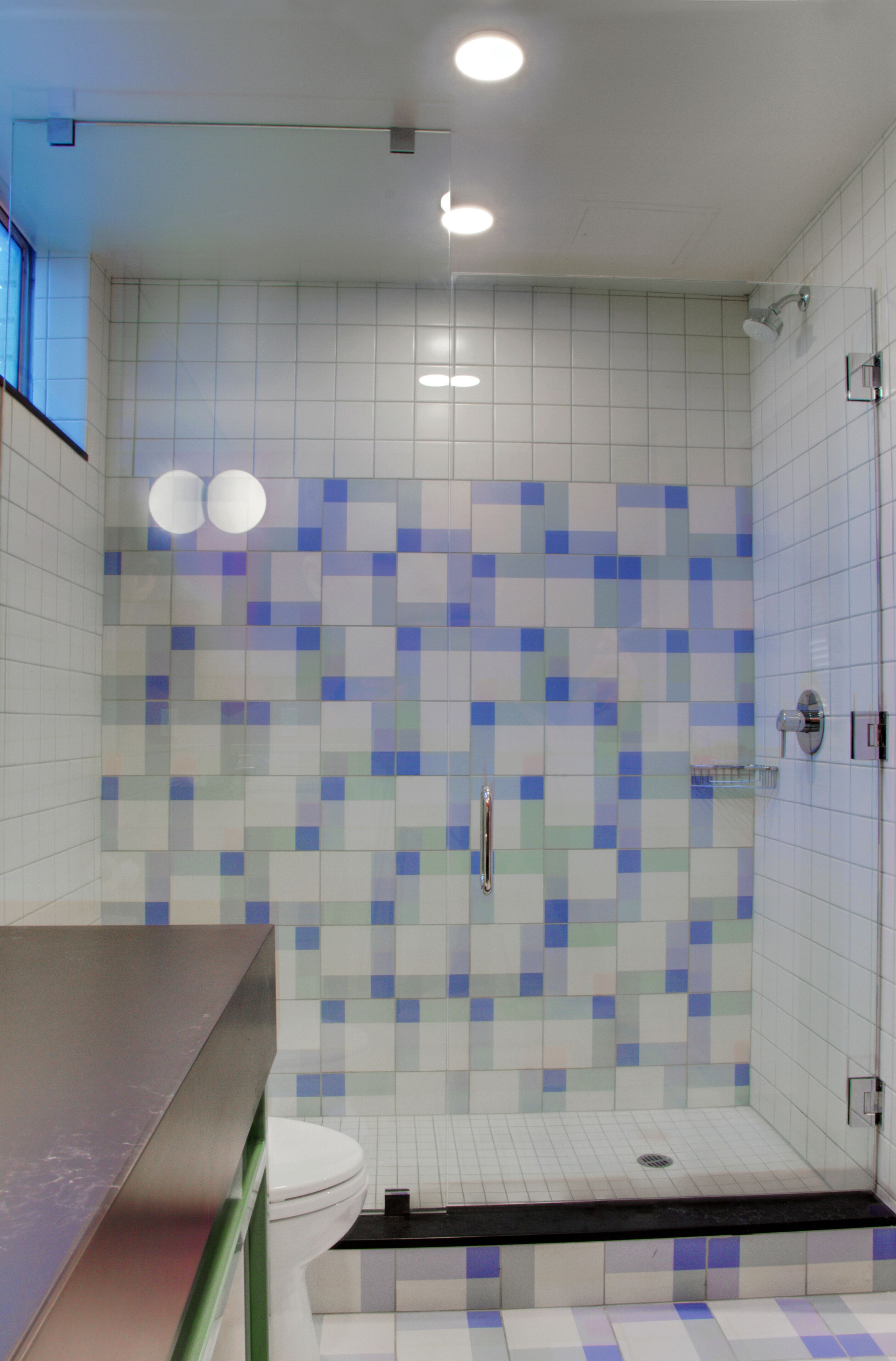 Een moderne badkamer met een douche, betegelde wanden, een toilet en een wastafel.
