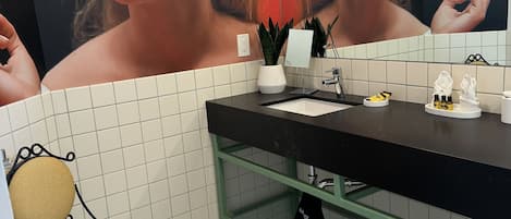A bathroom with a checkered floor, a black sink, a mirror, a towel rack, and a chair.