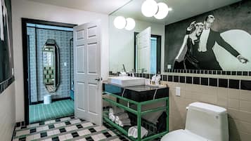 Ein modernes Badezimmer mit Schachbrettmuster-Boden, einem grünen Waschtisch und einer weißen Toilette, sowie einem großen Spiegel mit Beleuchtung.