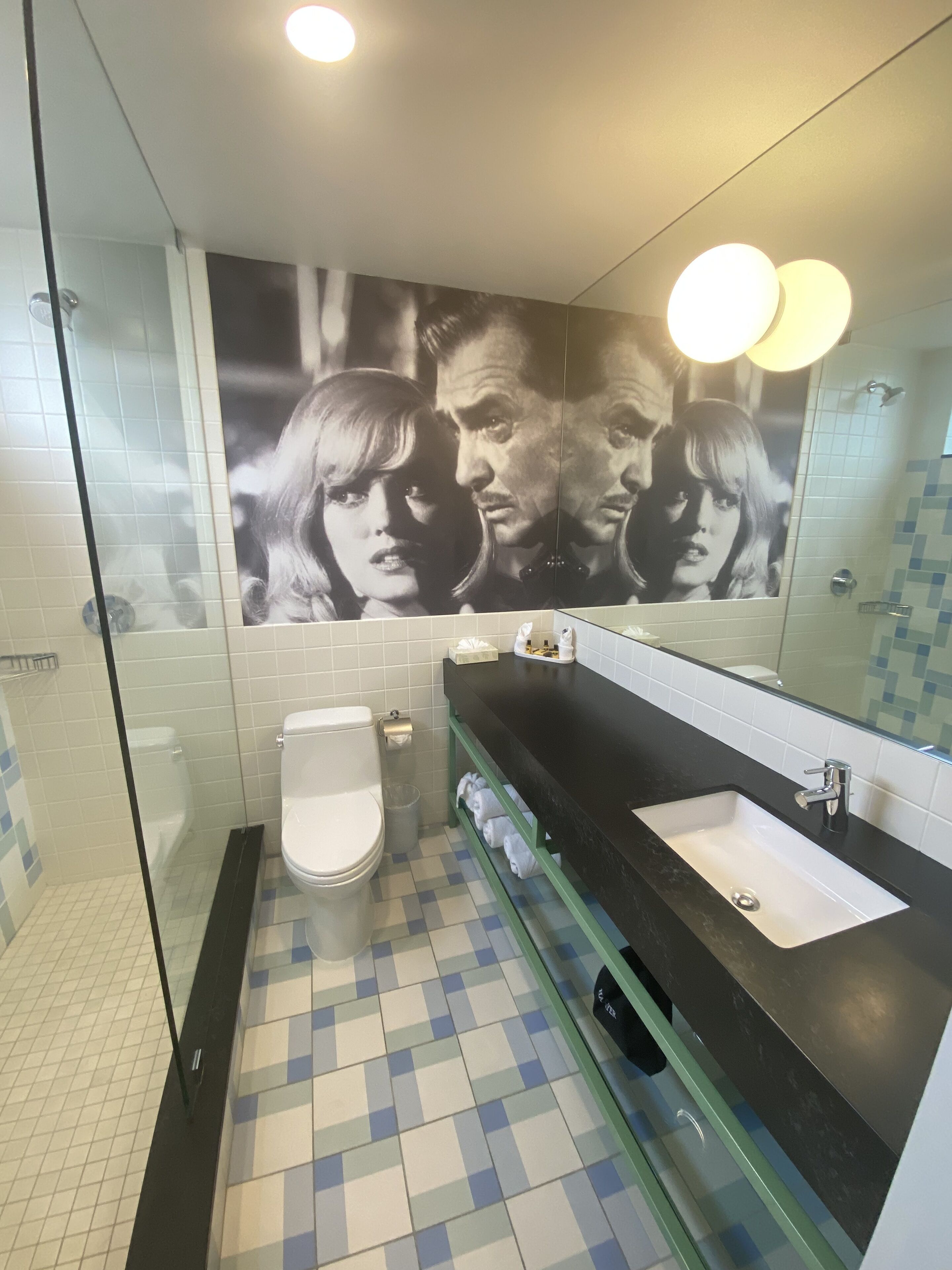 Een badkamer met een douchecabine van glas, een toilet, een wastafel met spiegel en een betegelde vloer.