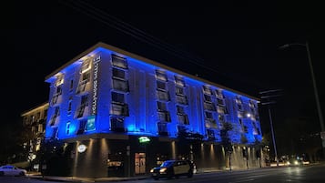 A multi-story hotel with a modern facade, illuminated by blue lighting.