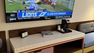 Un téléviseur diffusant un match de la NFL, une horloge et un livre sur une table de chevet.