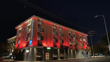 Een meerhoog hotel met een modern architectonisch ontwerp, met een opvallende rode gevel en een restaurant op de begane grond.