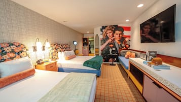 Ein Hotelzimmer mit zwei Betten, einem Schreibtisch, einem Fernseher und einem großen Poster an der Wand.