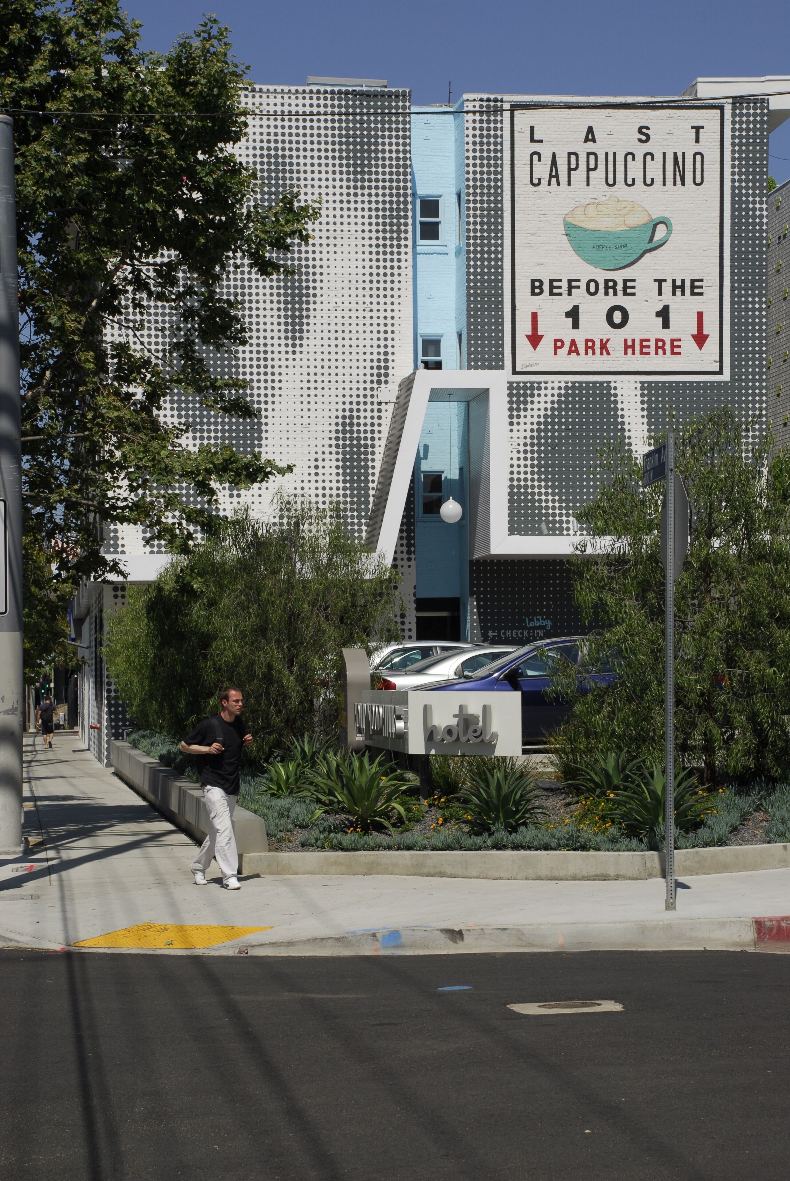 A modern building with a sign advertising the last cappuccino before the 101 parking area.