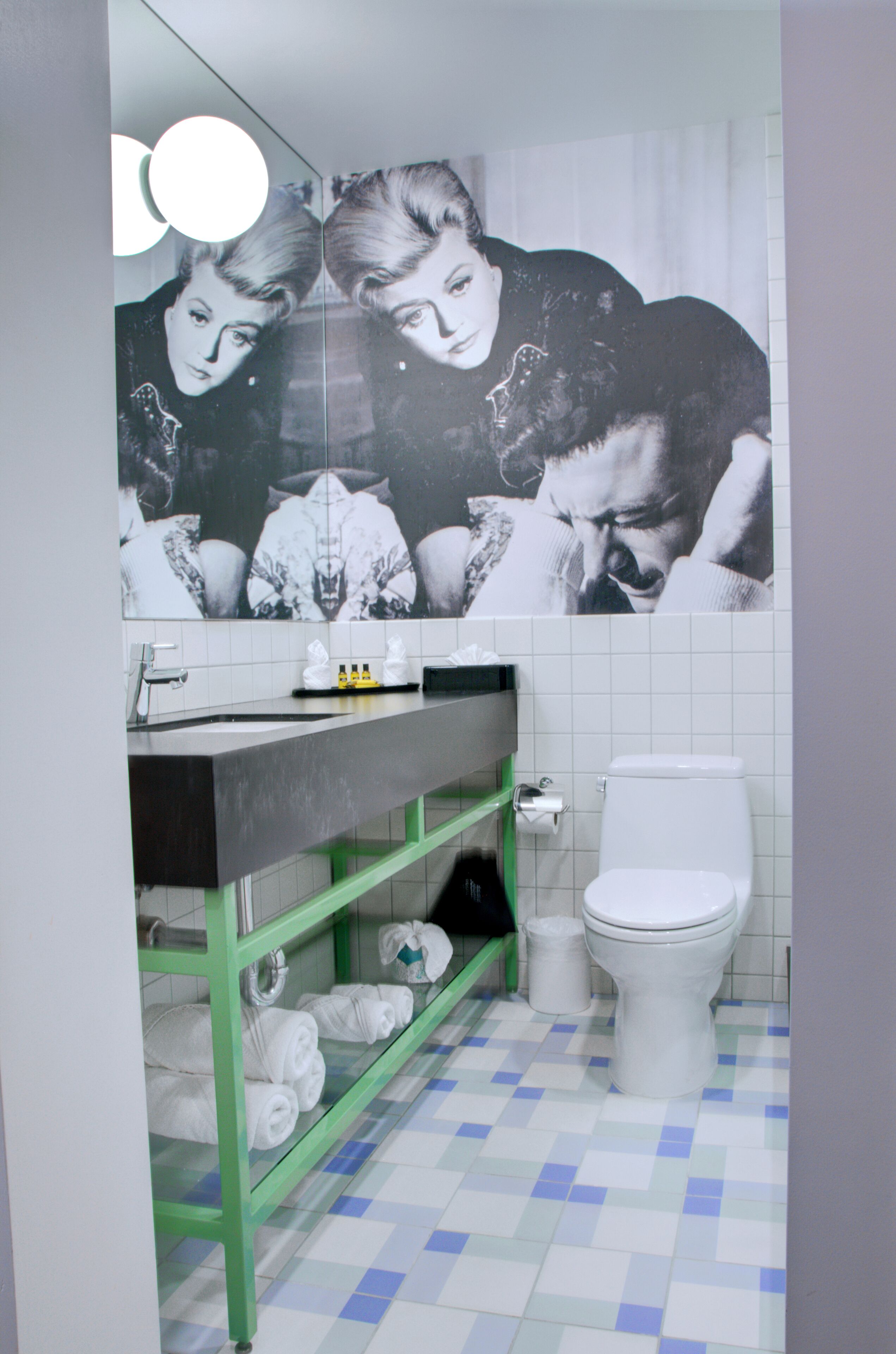 Un baño con un inodoro blanco, un perchero verde y un espejo sobre el lavamanos.