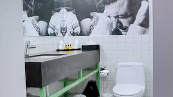 Un baño con un inodoro blanco, un perchero verde y un espejo sobre el lavamanos.