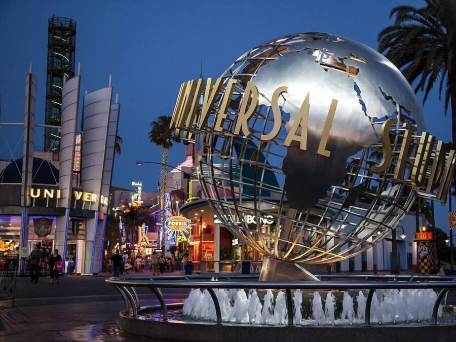 A large metallic globe with "UNIVERSAL" written on it, surrounded by a metal framework, with a water fountain in the foreground.