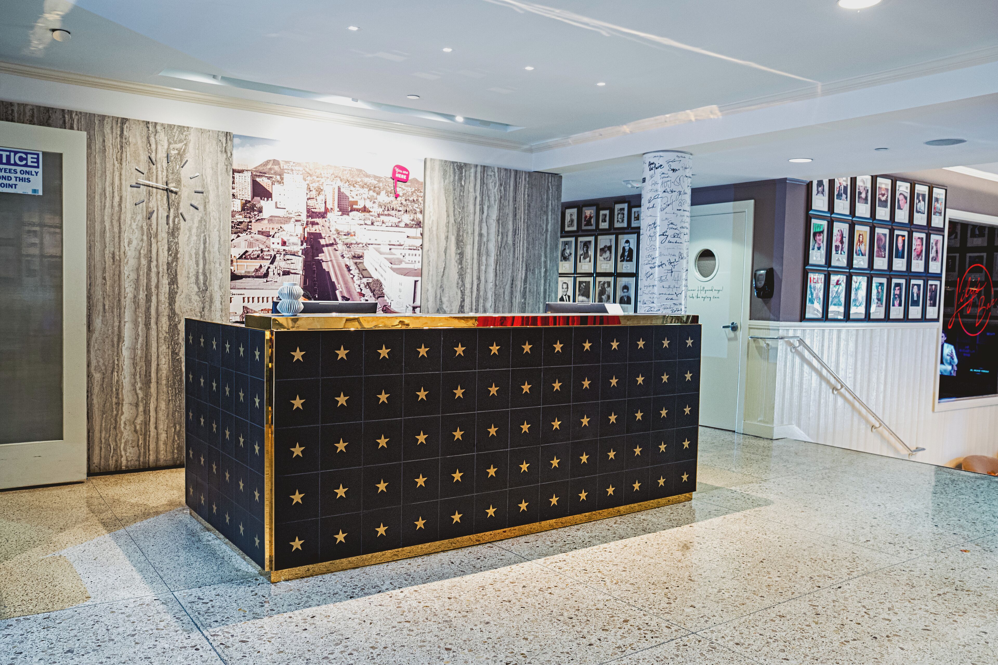 A reception area with a star-patterned counter, a cityscape mural, framed photos on the wall, and a staircase.